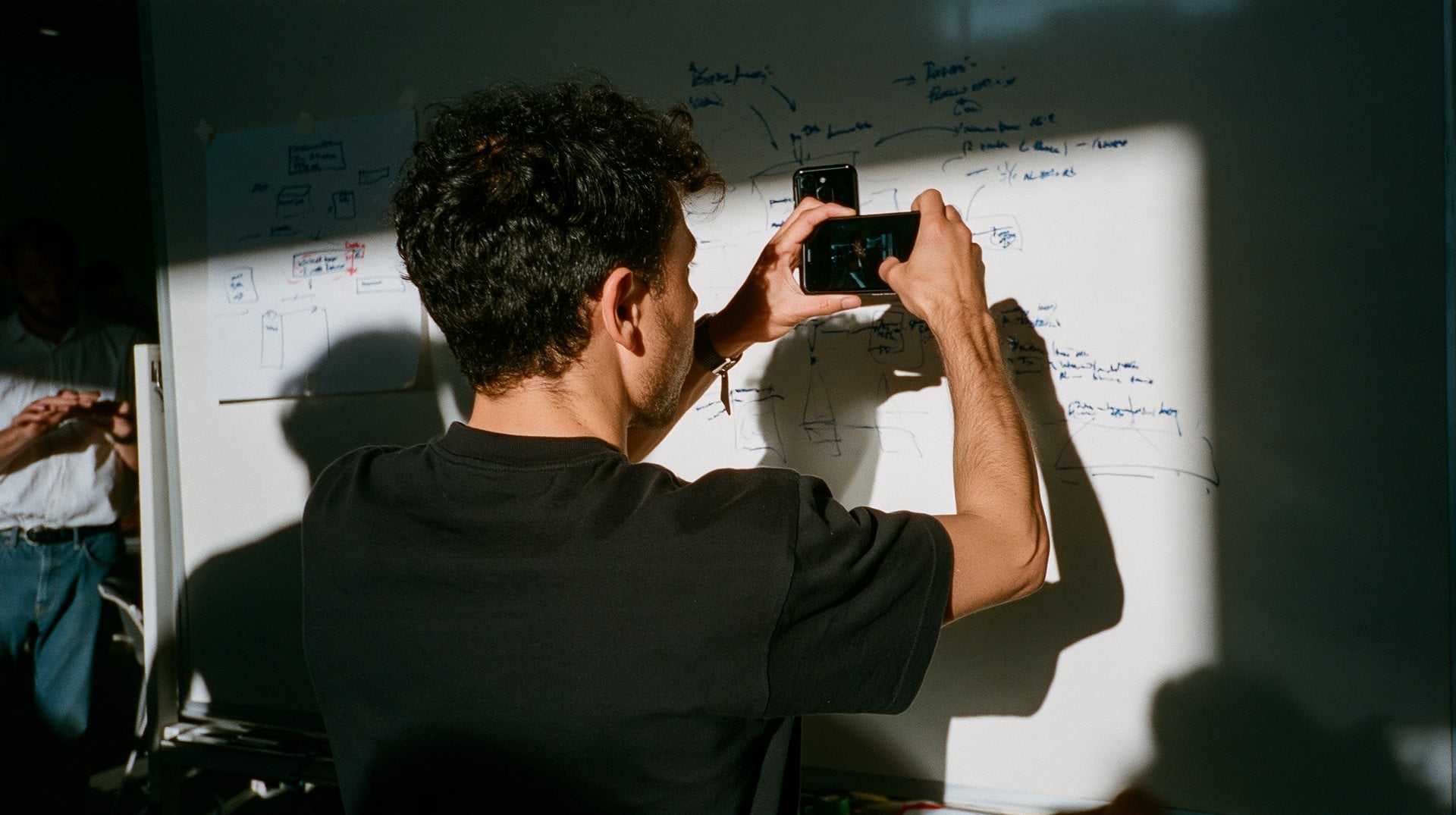 Someone photographing a whiteboard covered in flow diagrams